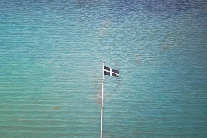 Flag above turquoise water — photograph by Monty Bray